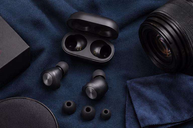 Wireless earbuds and a camera lens on navy fabric