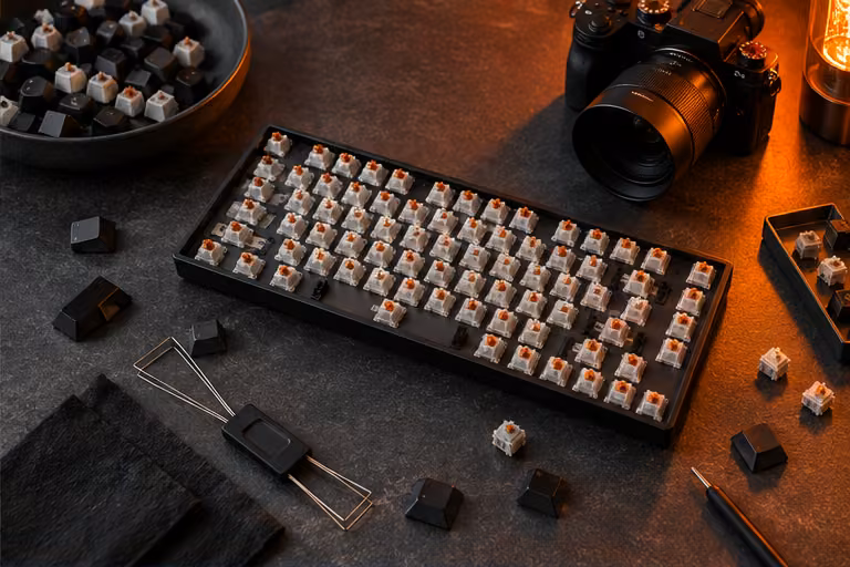 Mechanical keyboard parts and camera on a dark worktop